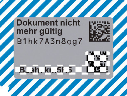 Es wird eine beispielhafte Abbildung der freigelegten Markierung mit Sicherheitscode der Zulassungsbescheinigung Teil II, wie zuvor beschrieben, dargestellt. Im Silbergrauen Feld steht der Text „Dokument nicht mehr gültig.“ Darunter befindet sich ein QR-Code und eine beispielhafte Zeichenabfolge.