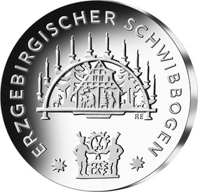 Die Bildseite zeigt als Hauptelement einen hölzernen Schwibbogen aus dem Jahr 1925, der Motive der heimatlichen Stube mit Vorbereitungen zum Heiligen Abend abbildet. Das Emblem der beiden Bergmänner mit den sächsischen Kurschwertern und Schlägel sowie Eisen ist im unteren Bereich der Münze abgebildet. Der Schriftzug „Erzgebirgischer Schwibbogen“ wird entlang des Münzrunds gesetzt.